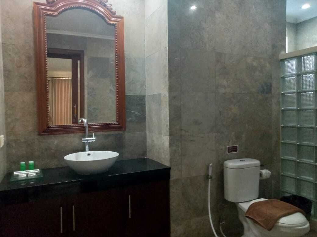 A bathroom with a sink, mirror, toilet, and tiled walls.