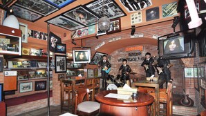A music-themed room with a brick wall, posters, and memorabilia. - Sekuta Condo Suites (Denpasar)
