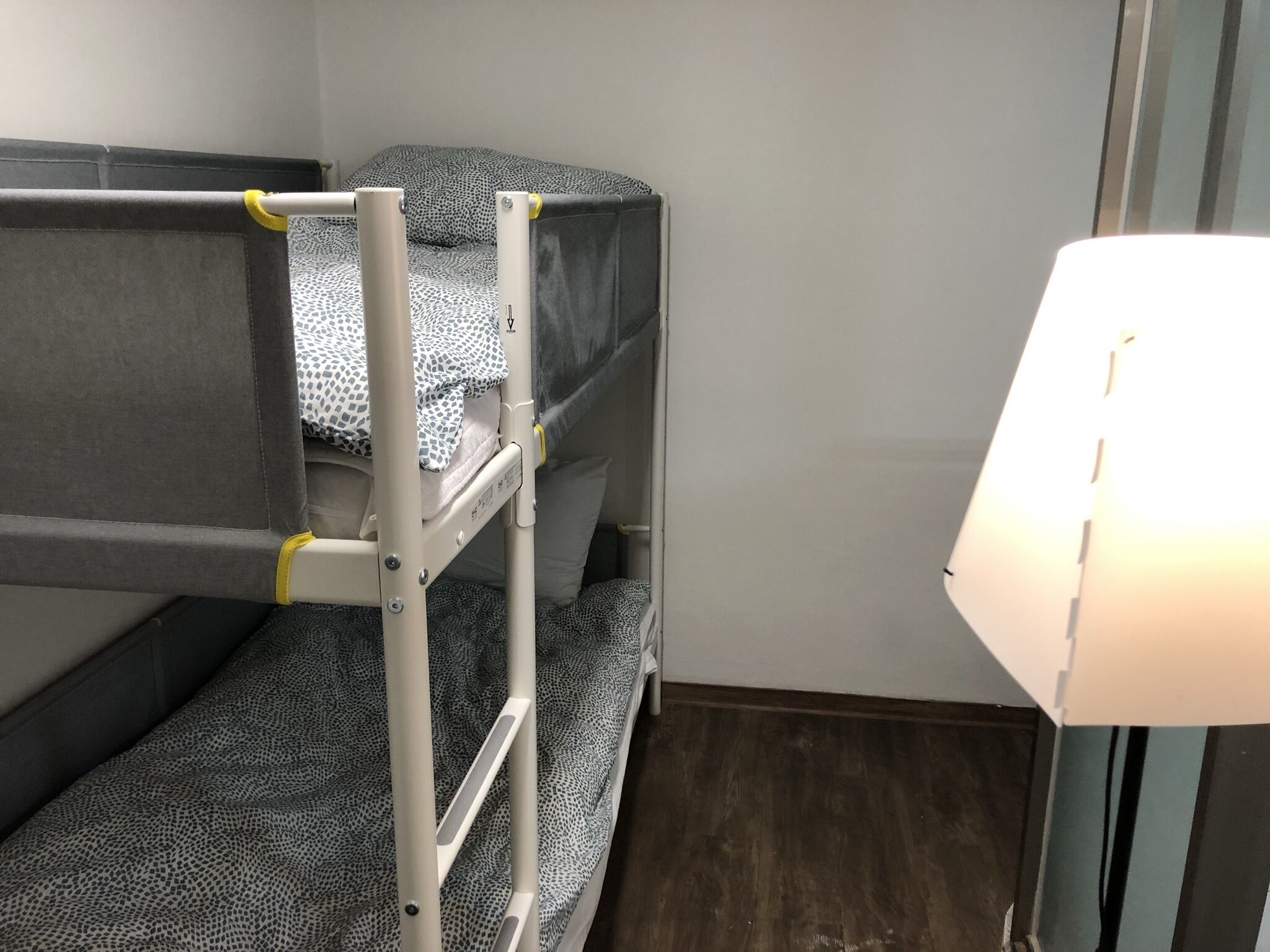 A bunk bed room with a ladder, a bedside table, and a lamp.