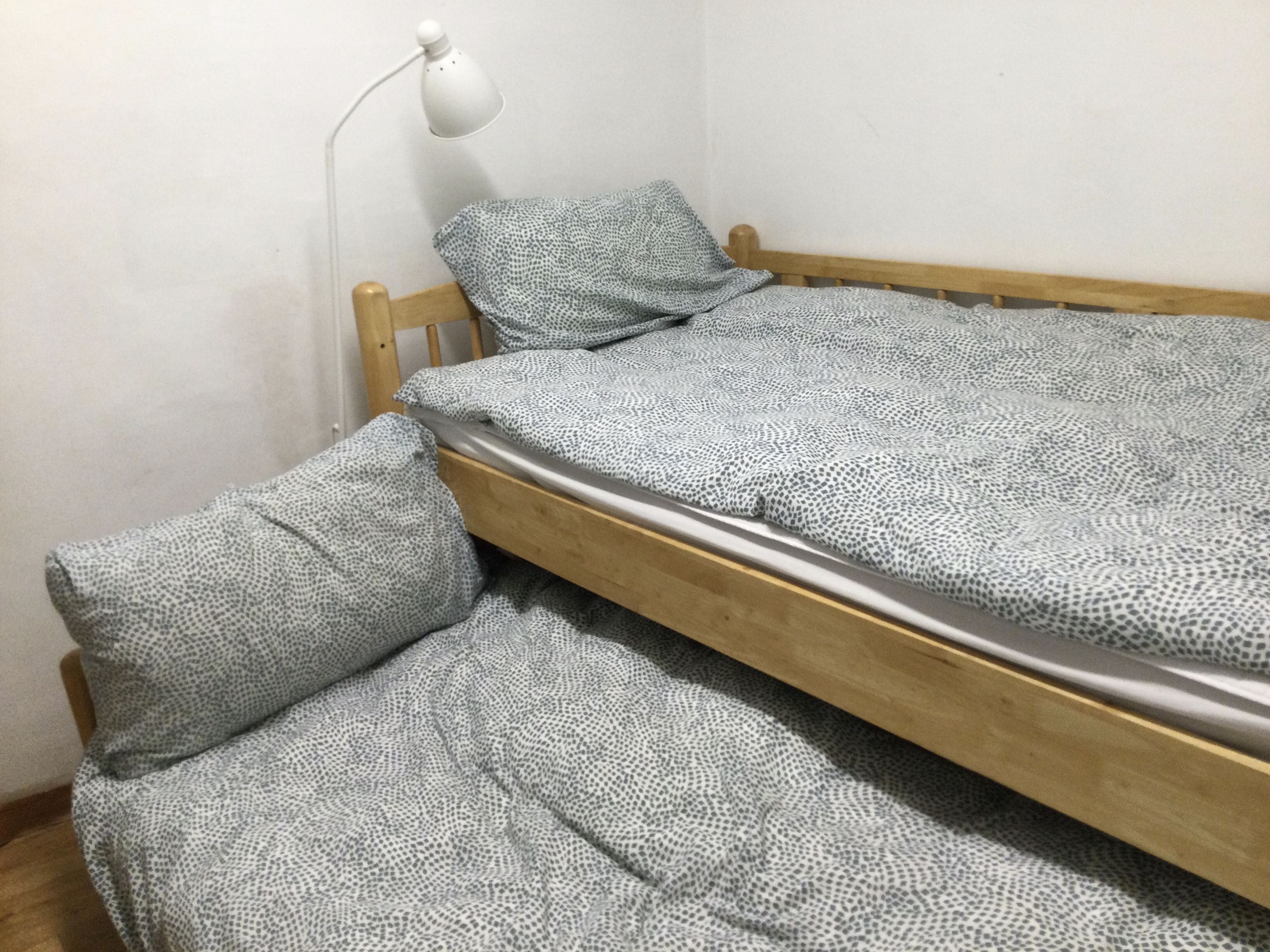 Une petite chambre avec un lit simple, un cadre en bois et une literie à motifs.
