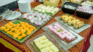 A buffet table with various food items including fruits, pastries, and desserts.