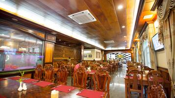 Un restaurante con mesas y sillas de madera, manteles individuales rojos y un acuario al fondo.