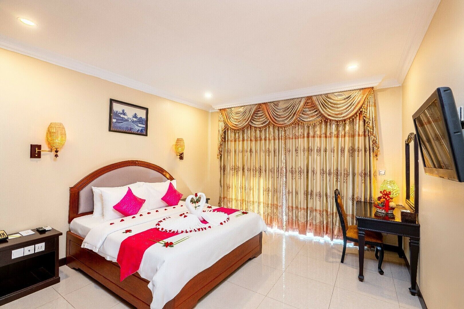A hotel room with a large bed, a desk with a chair, a TV, and a window with curtains.