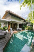 Eine moderne Villa mit Pool, Holzterrasse und üppiger Bepflanzung.