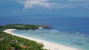 Un paisaje costero con playa, aguas cristalinas y abundante vegetación.