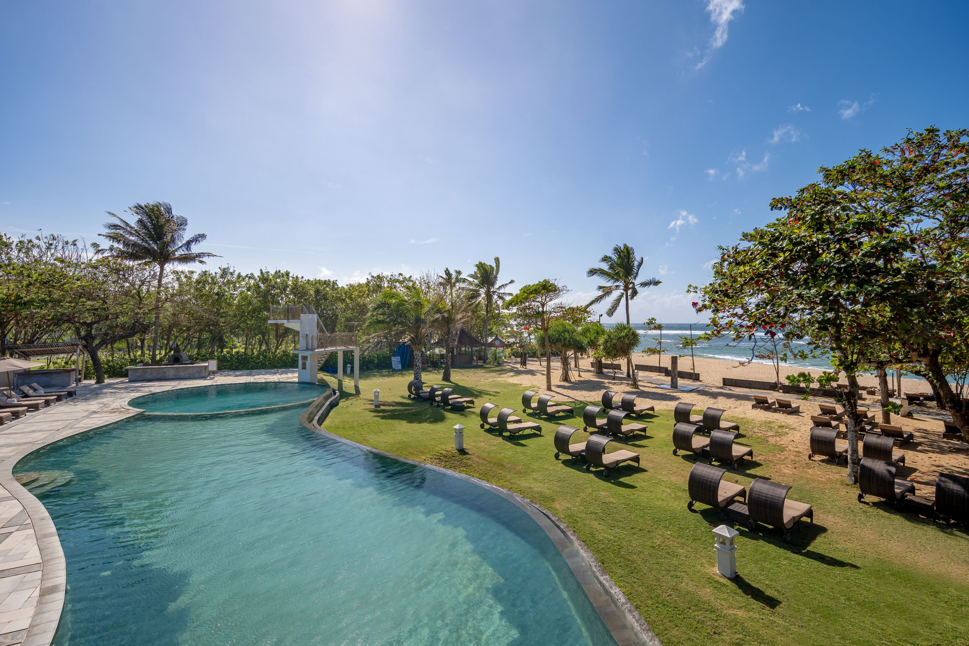 A pool area with lounge chairs and a view of the beach.