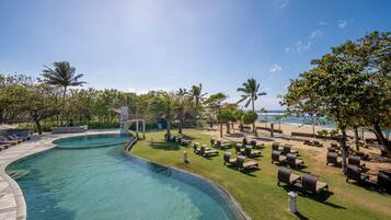 A pool area with lounge chairs and a view of the beach.