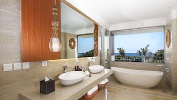 Ein modernes Badezimmer mit einer großen Badewanne, zwei Waschbecken, einem großen Spiegel und Meerblick.