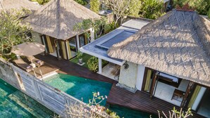 Un resort con varias cabañas sobre el agua, una piscina y abundante vegetación.