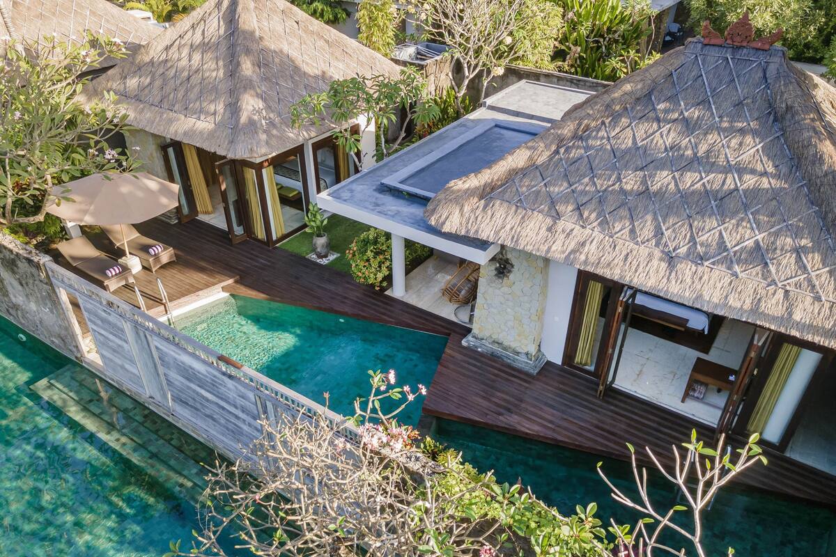 Un resort con varias cabañas sobre el agua, una piscina y abundante vegetación.