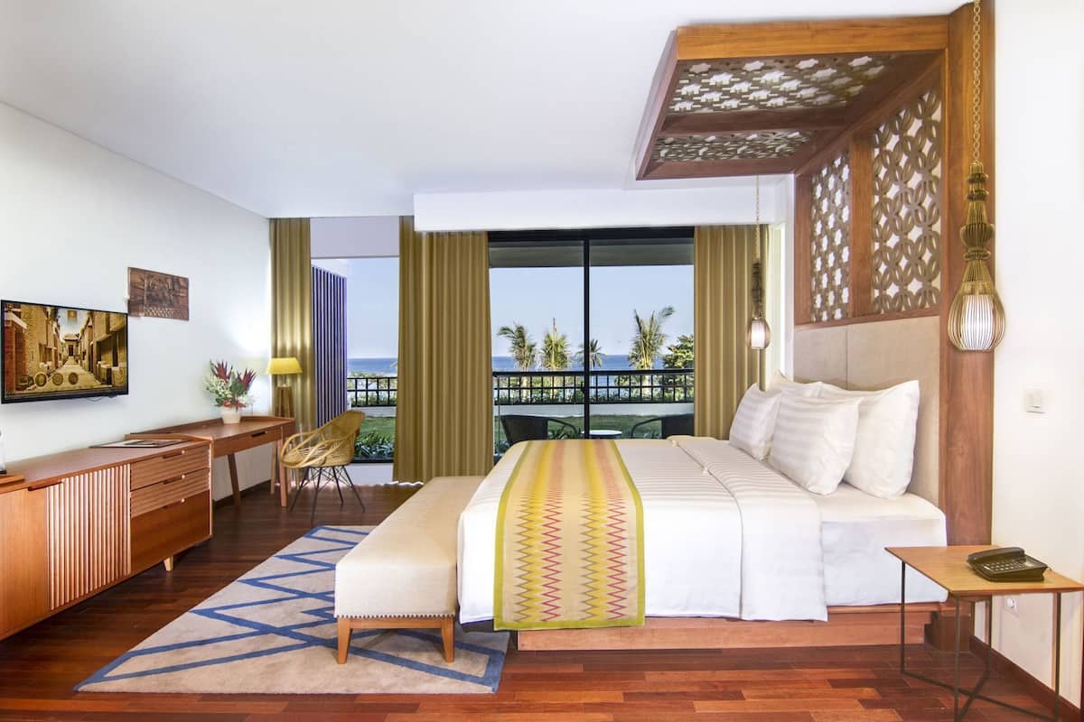 Habitación de hotel con cama, escritorio, silla y vista al océano.