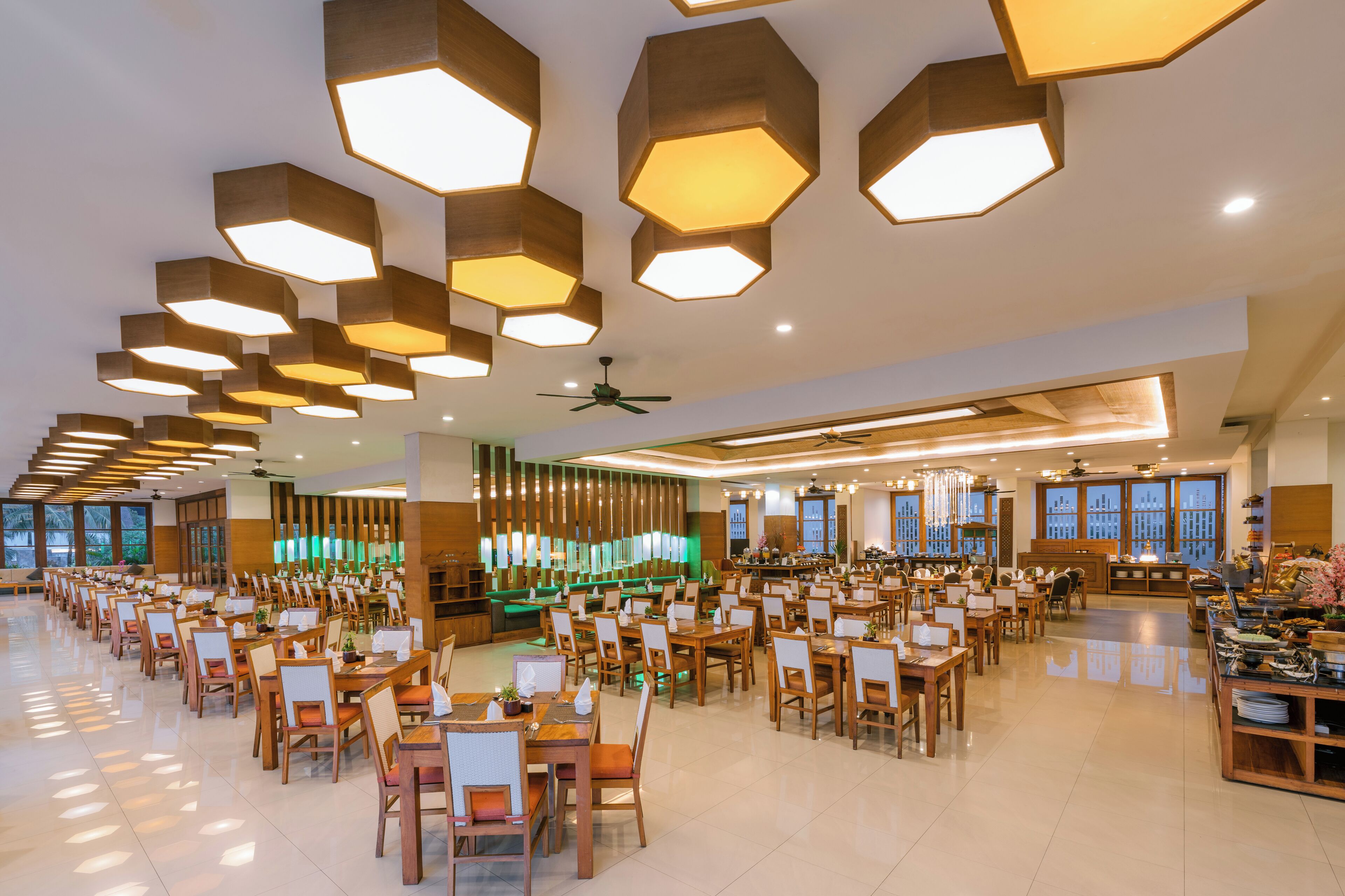 Un comedor amplio con luminarias hexagonales en el techo, varias mesas y sillas.