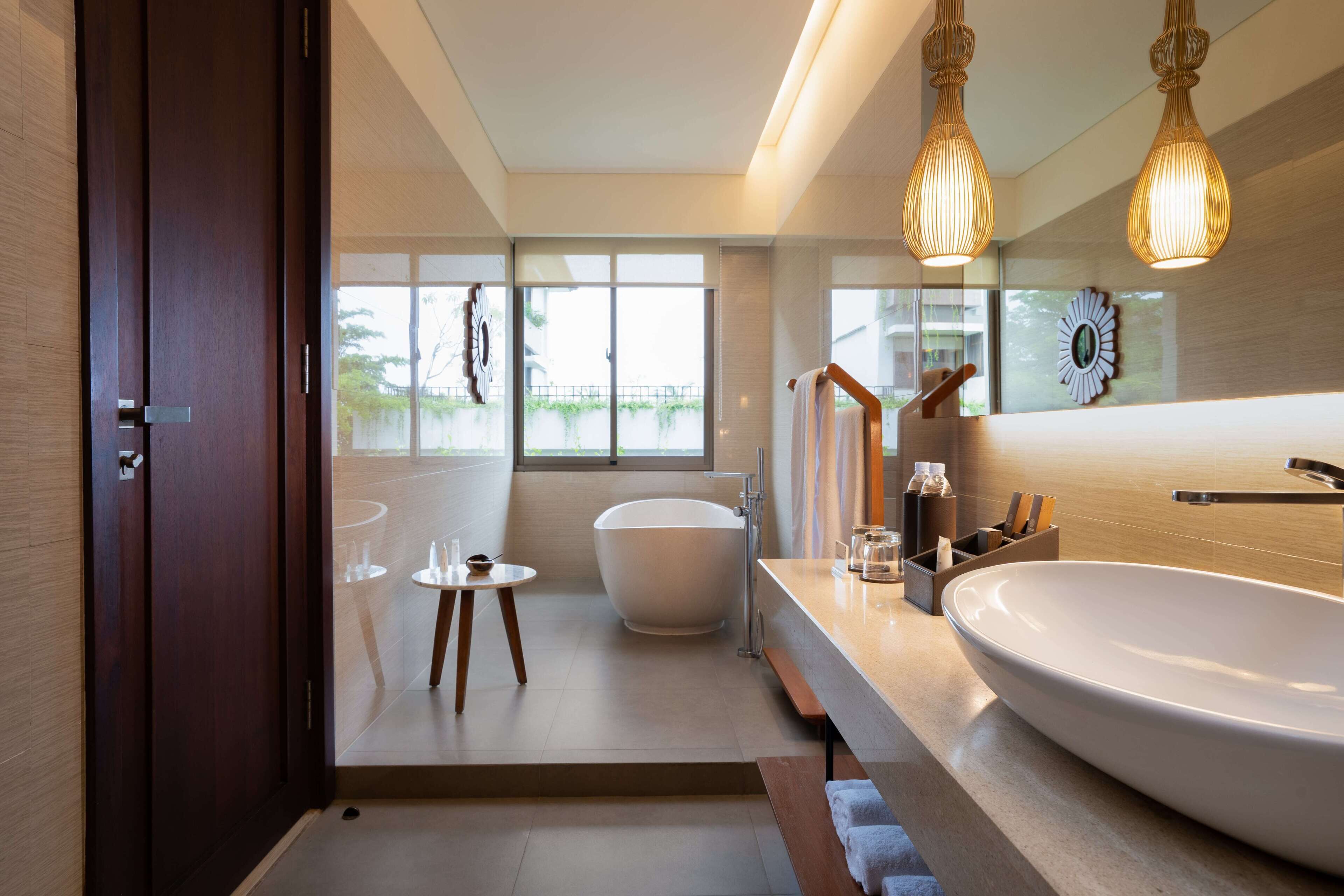 A modern bathroom with a freestanding bathtub, a large sink, and a small table with glasses.