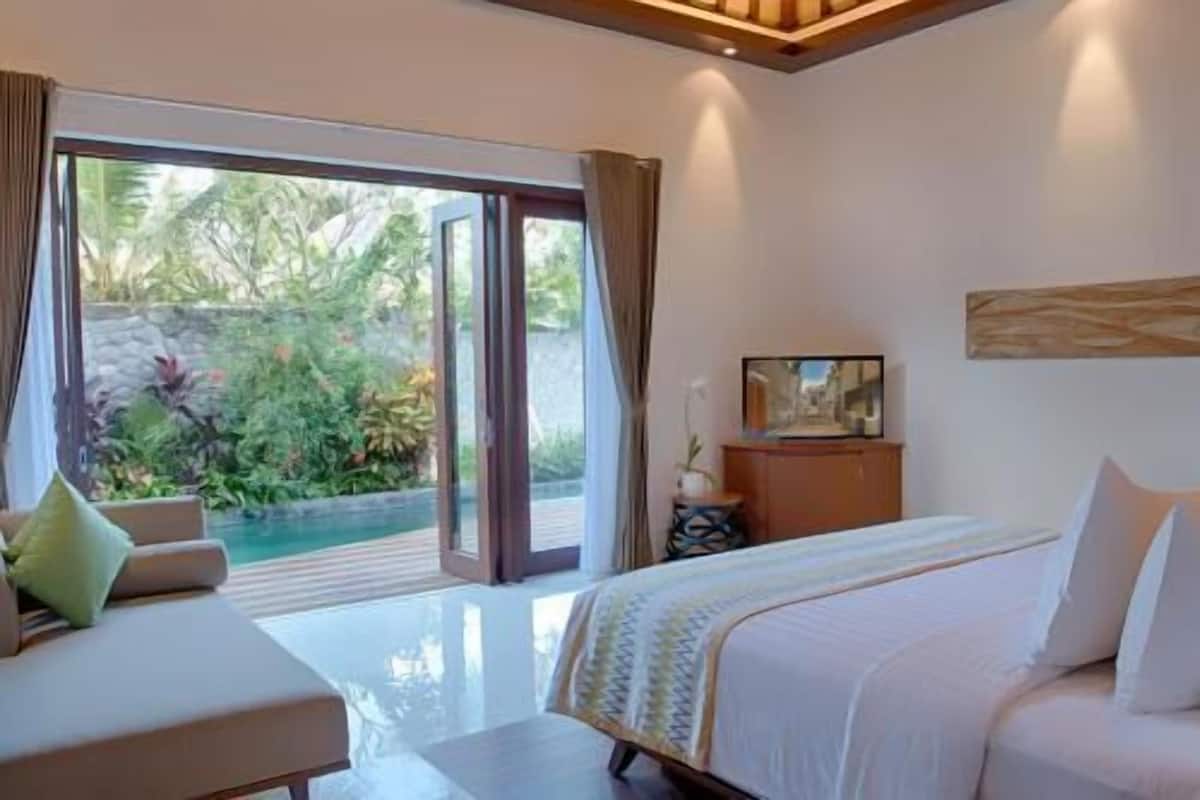 Un dormitorio con cama, televisión y vistas a una piscina y vegetación.