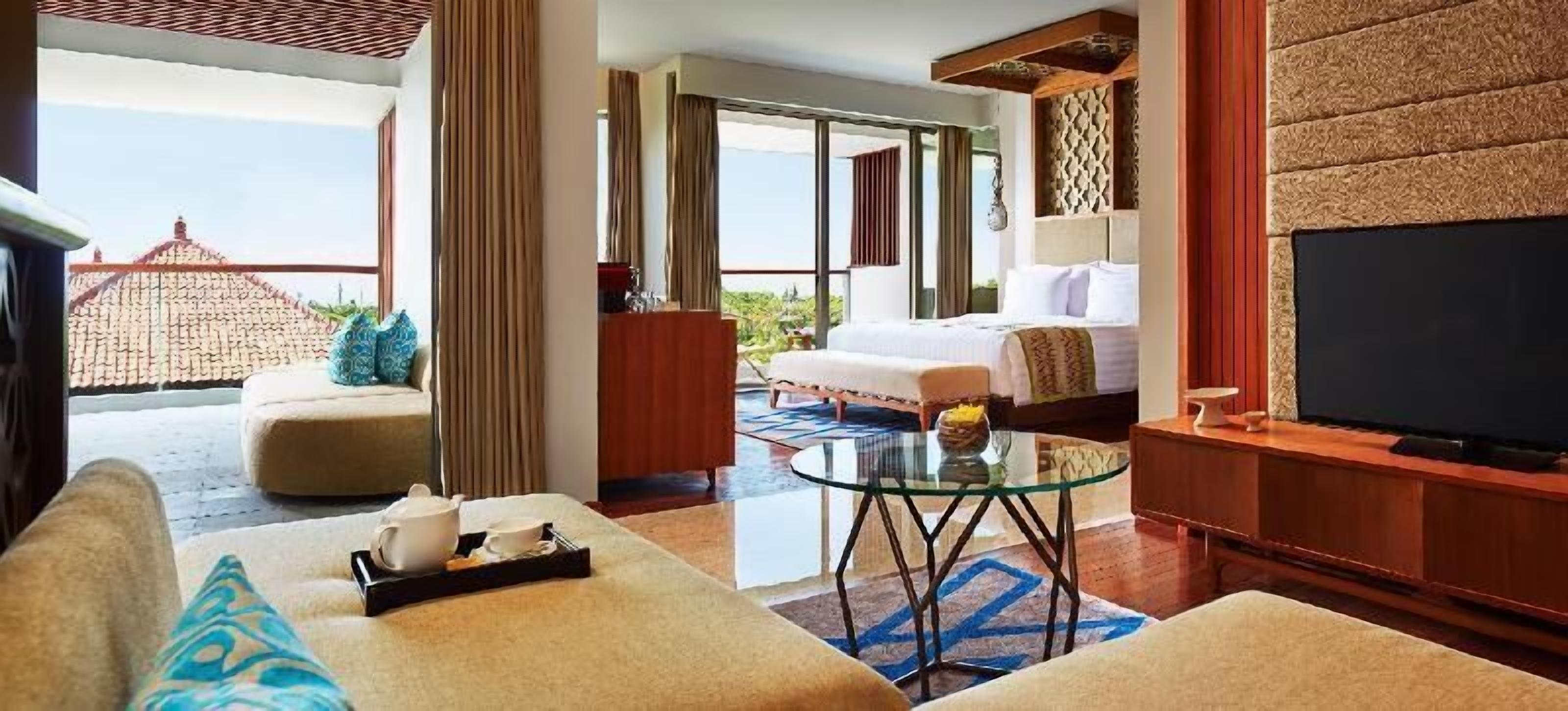 A hotel room with a bed, a TV, a glass coffee table, a sofa, and a balcony with a view.