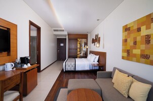 Ein Hotelzimmer mit einem Bett, einer Couch, einem Schreibtisch mit Kaffeemaschine und einem Fernseher.