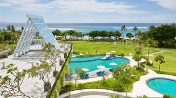 Ein Resort mit großem Poolbereich, einer Glasarchitektur und Blick auf den Ozean.