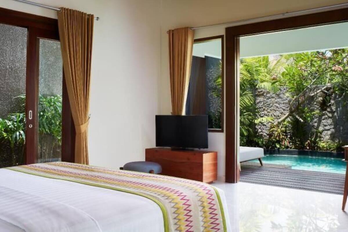 Un dormitorio con una cama, televisión, escritorio y silla.