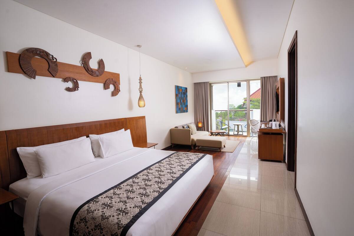 Habitación de hotel con una cama grande, un escritorio, una silla y vistas al exterior.