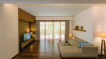 Una sala de estar moderna con suelo de madera, un sofá, un televisor y una mesa de vidrio.