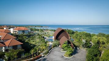 A resort with a distinctive curved building, a pool, and a view of the ocean.