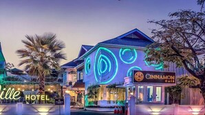 Un hotel de diseño moderno, con luces de neón y un cartel destacado para 'Cinnamon Cafe'.