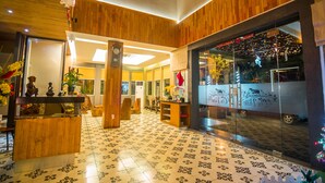 Un hall de hotel con paneles de madera, un mostrador de recepción y un escaparate de vidrio.