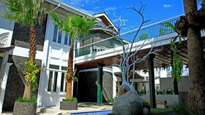 Un edificio moderno con piscina, palmeras y un balcón.
