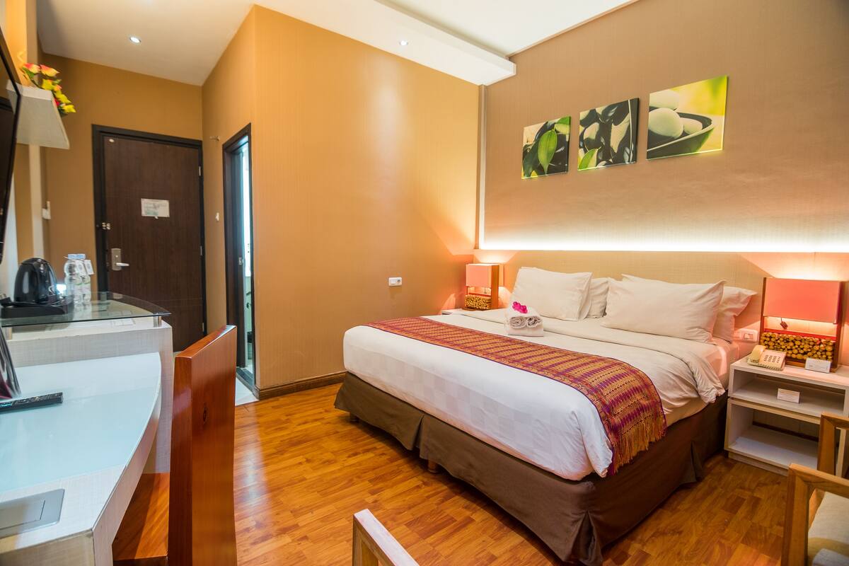 A hotel room with a bed, bedside tables, a desk, and a chair.