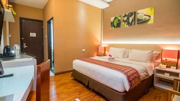 A hotel room with a bed, bedside tables, a desk, and a chair.