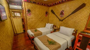 Una habitación con dos camas, piso de madera, una mesita y una paleta en la pared.