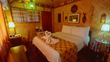 Une chambre d’hôtel comprenant un lit, un bureau, une chaise, une lampe et un mur décoré.