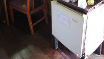 Una habitación con un escritorio de madera, una silla y un refrigerador pequeño.