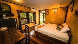 Una habitación con cama, escritorio y ventana con vista a la vegetación.