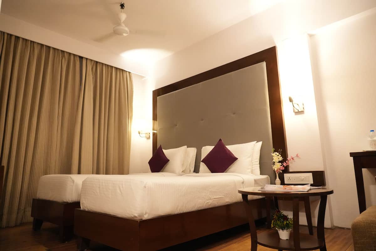 A hotel room with a large bed, two bedside tables, a small desk, and a chair.