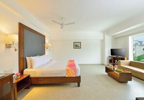 A hotel room with a bed, a television, a sofa, and a window with a city view. - Ginger Bhavnagar, Kalubha Road (Bhavnagar)