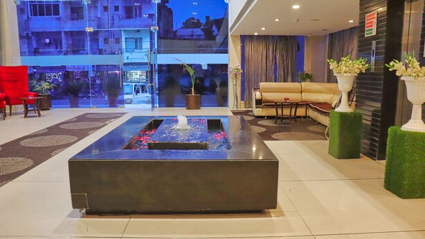 A modern lobby with a central water feature, comfortable seating, and a view of the cityscape. - Hotel Clarks Collection Bhavnagar (Bhavnagar)