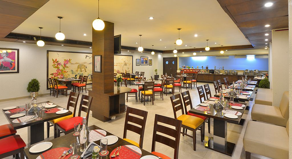 Un restaurante con varias mesas y sillas, una zona de mostrador y obras de arte en las paredes.