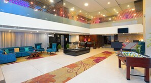 A spacious lobby with a high ceiling, a reception desk, seating area, and a foosball table. - Ginger Bhavnagar, Kalubha Road (Bhavnagar)