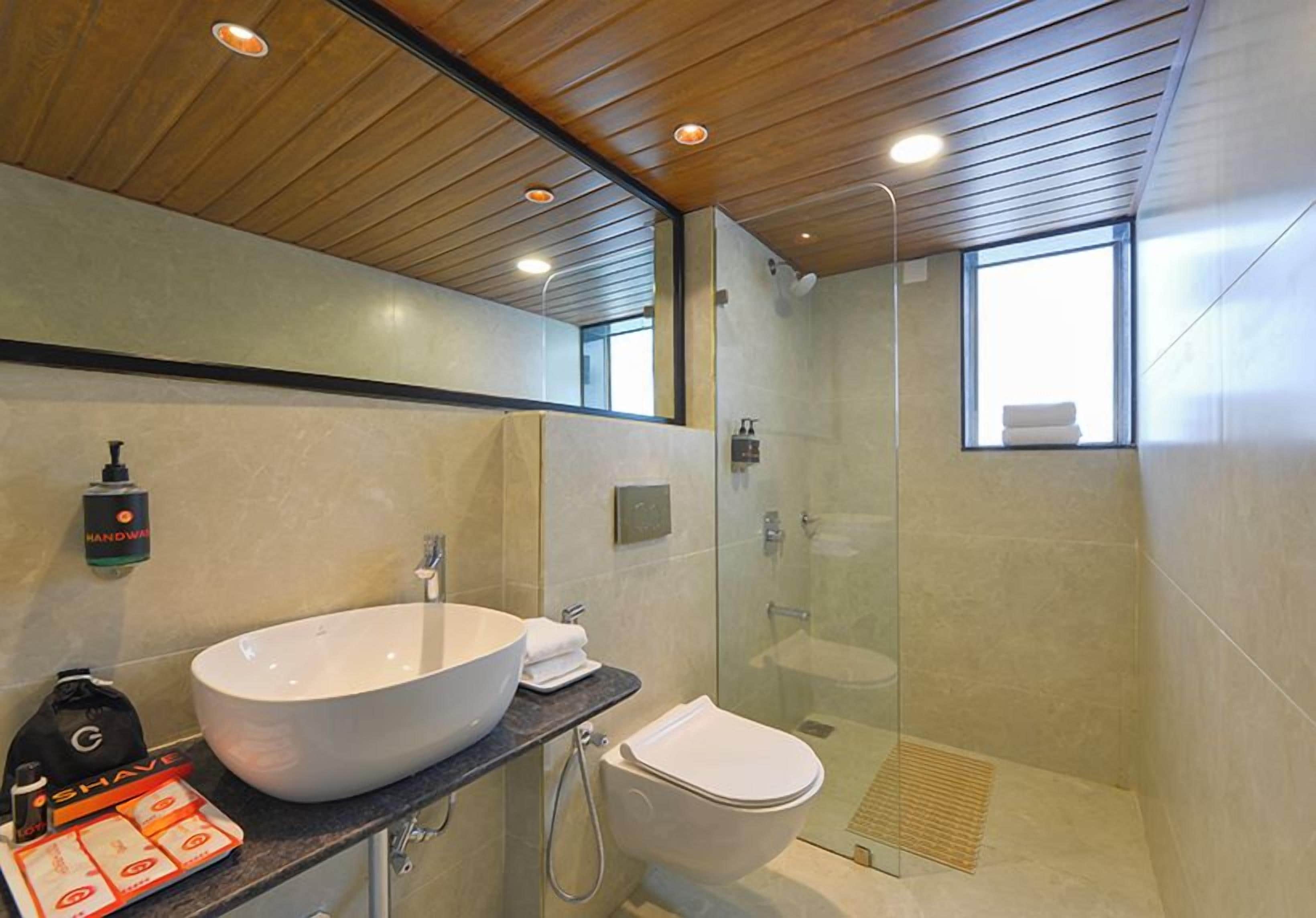 Une salle de bain moderne avec un grand lavabo sur pied, des toilettes et une douche à parois de verre.