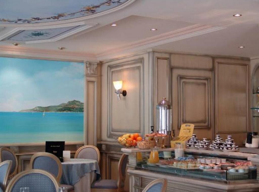 A dining area with a view of the sea, a buffet with various food items, and a decorative ceiling.