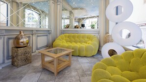 A spacious room with a high ceiling, large windows, and a yellow sofa.