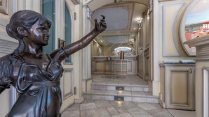 A statue in a hallway with steps leading to a mirrored area.
