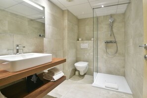 A modern bathroom with a sink, toilet, shower, and bathtub.