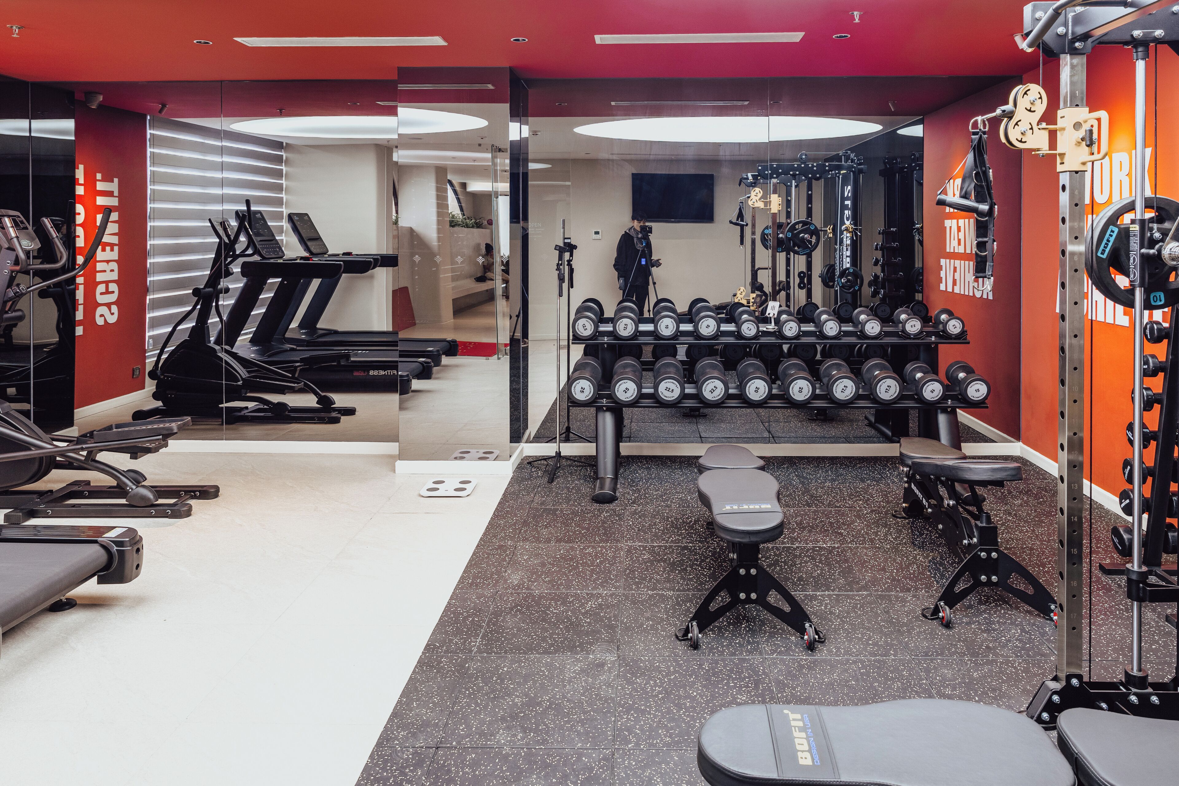 A gym with treadmills, dumbbells, and weight machines.