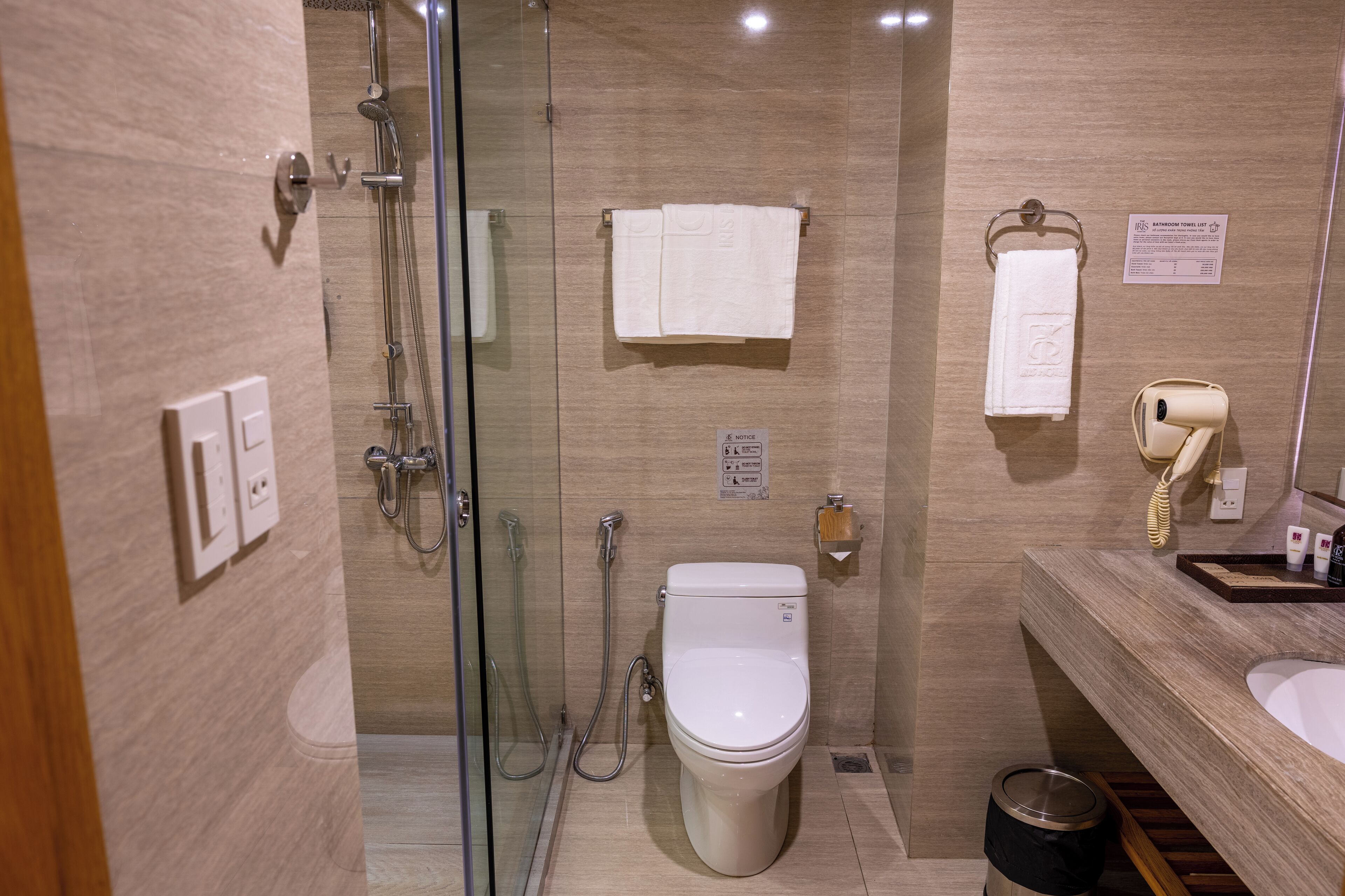 A modern bathroom with a glass-enclosed shower, a toilet, a sink with a mirror, and a towel rack.