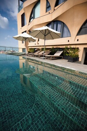 A modern hotel with a rooftop infinity pool, lounge chairs, and umbrellas. - The IRIS Signature Hotel & Spa (Can Tho)