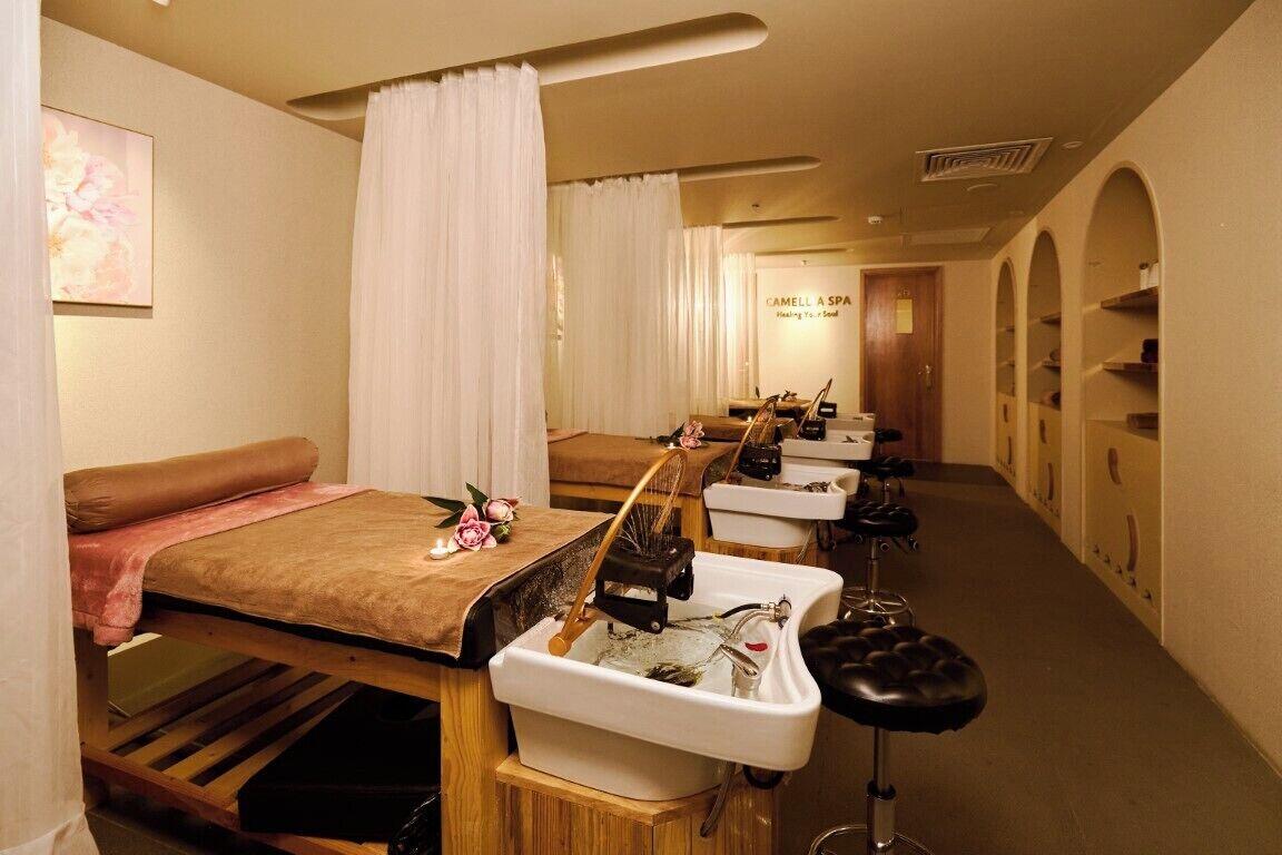 A spa room with a massage table, a foot bath, and a mirror.