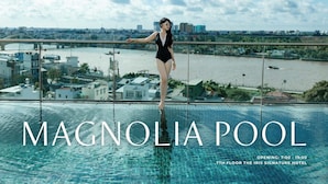 A woman balancing on the edge of a pool with a cityscape view. Text indicates "THE IRIS SIGNATURE HOTEL" and "MAGNOLIA POOL" with opening hours. - The IRIS Signature Hotel & Spa (Can Tho)