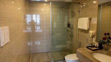 Un baño moderno con cabina de ducha de vidrio, tocador con lavabo y inodoro.